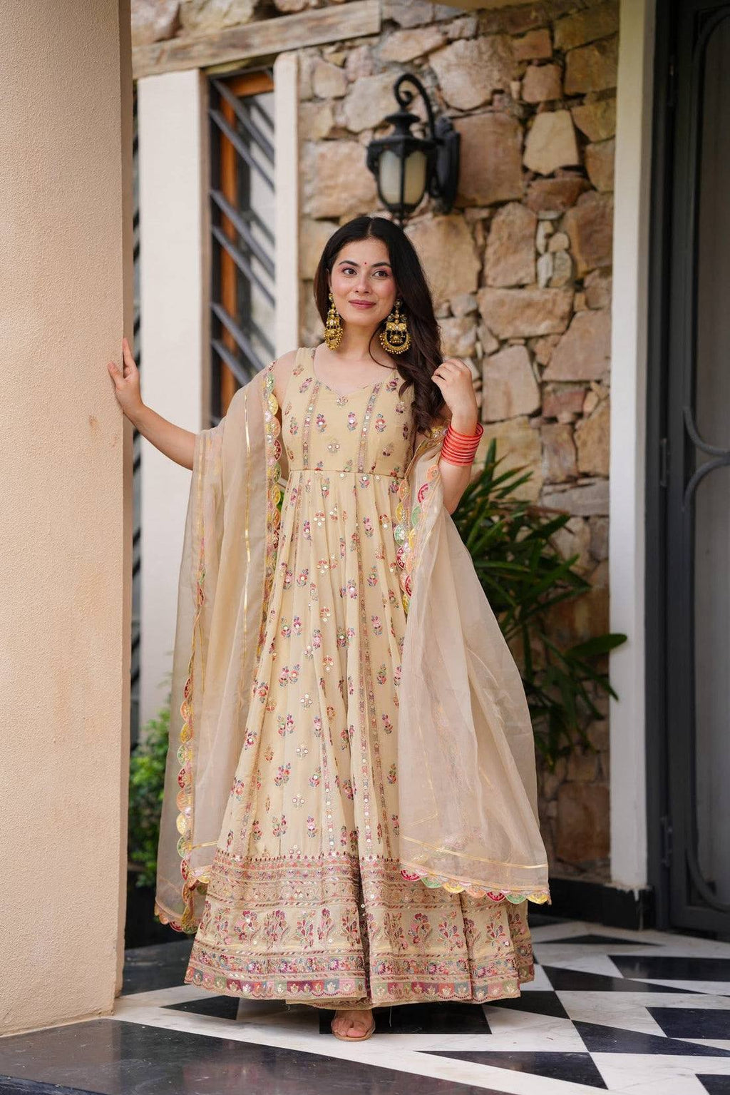 Woman in a beige, embroidered Anarkali gown.